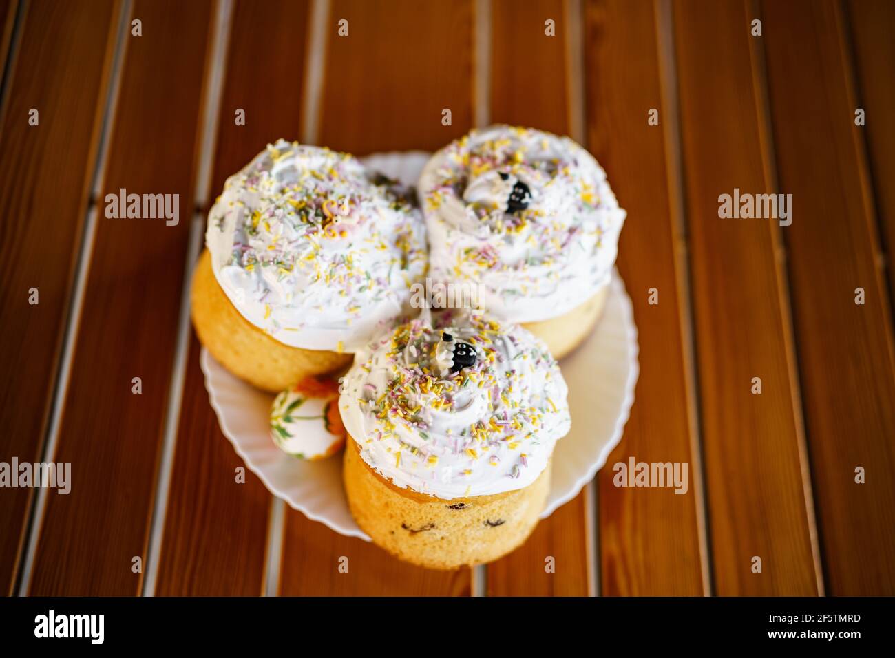 Three Easter cakes on a plate on a wooden table. Stock Photo