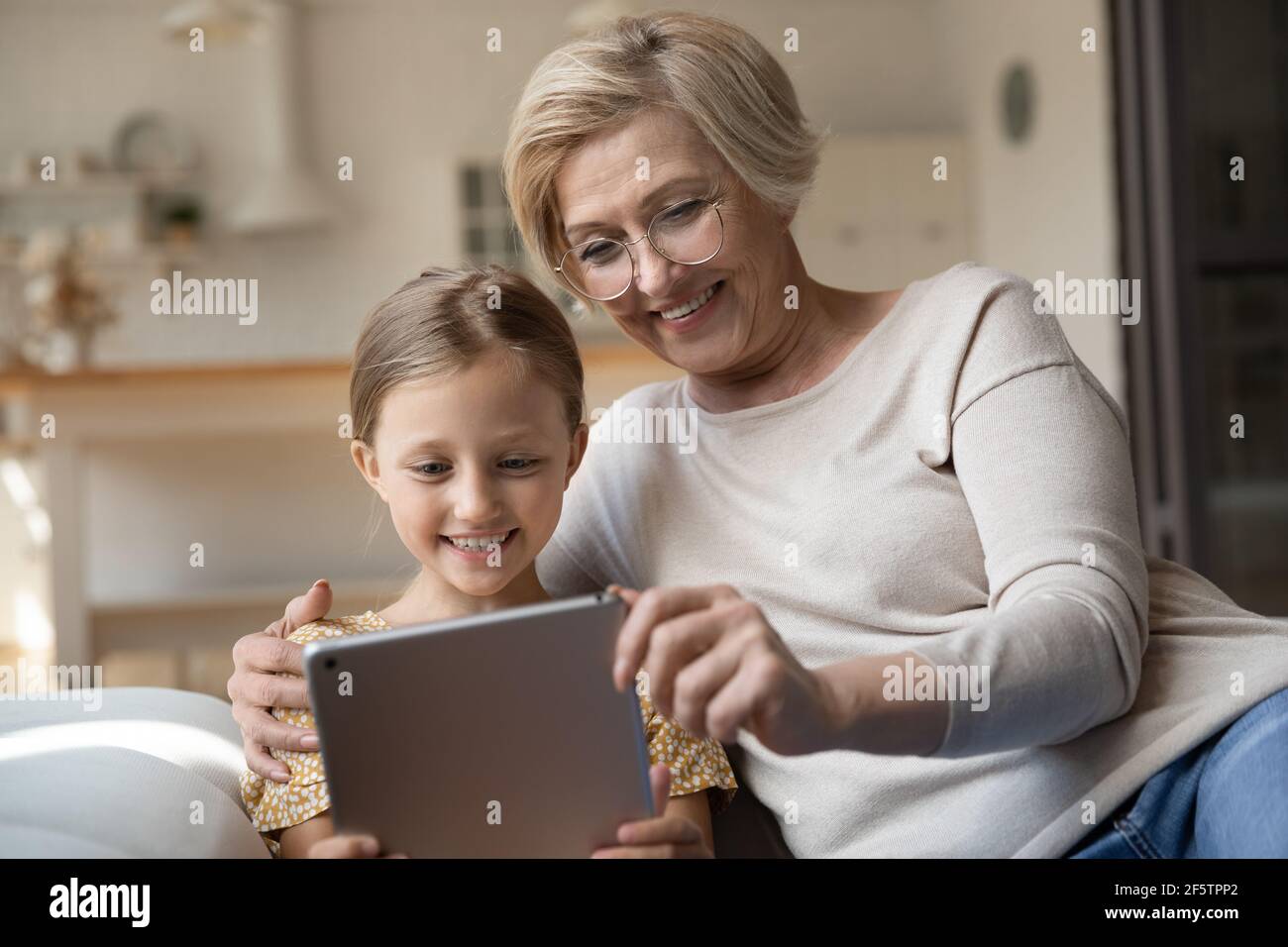 Smiling granny and small granddaughter use tablet Stock Photo