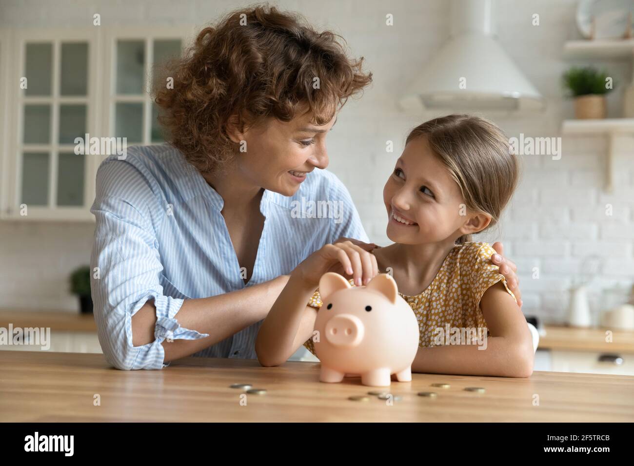 Happy young mom and daughter saving for future Stock Photo - Alamy