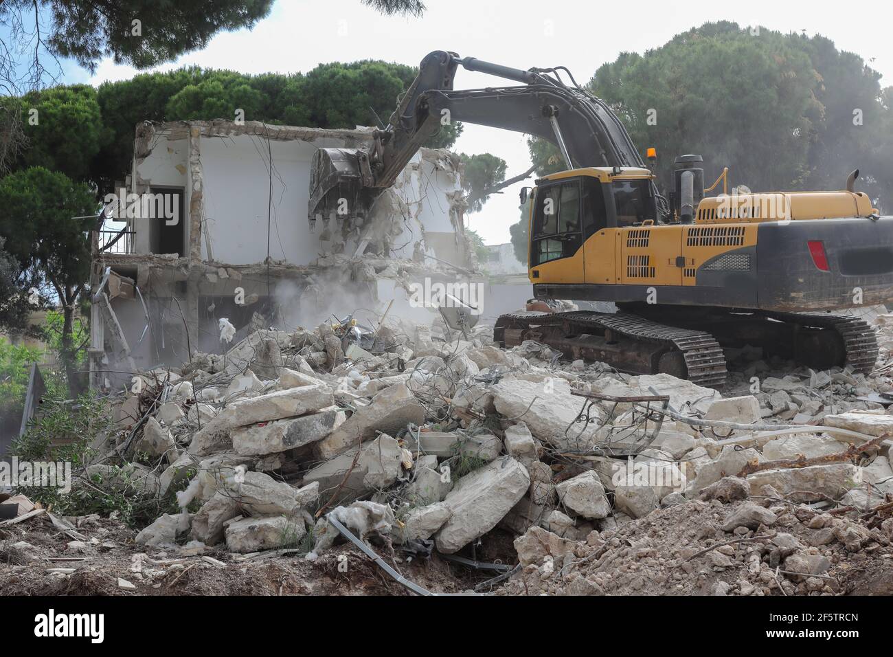 Excavator demolishing barracks for new construction project.  Stock Photo