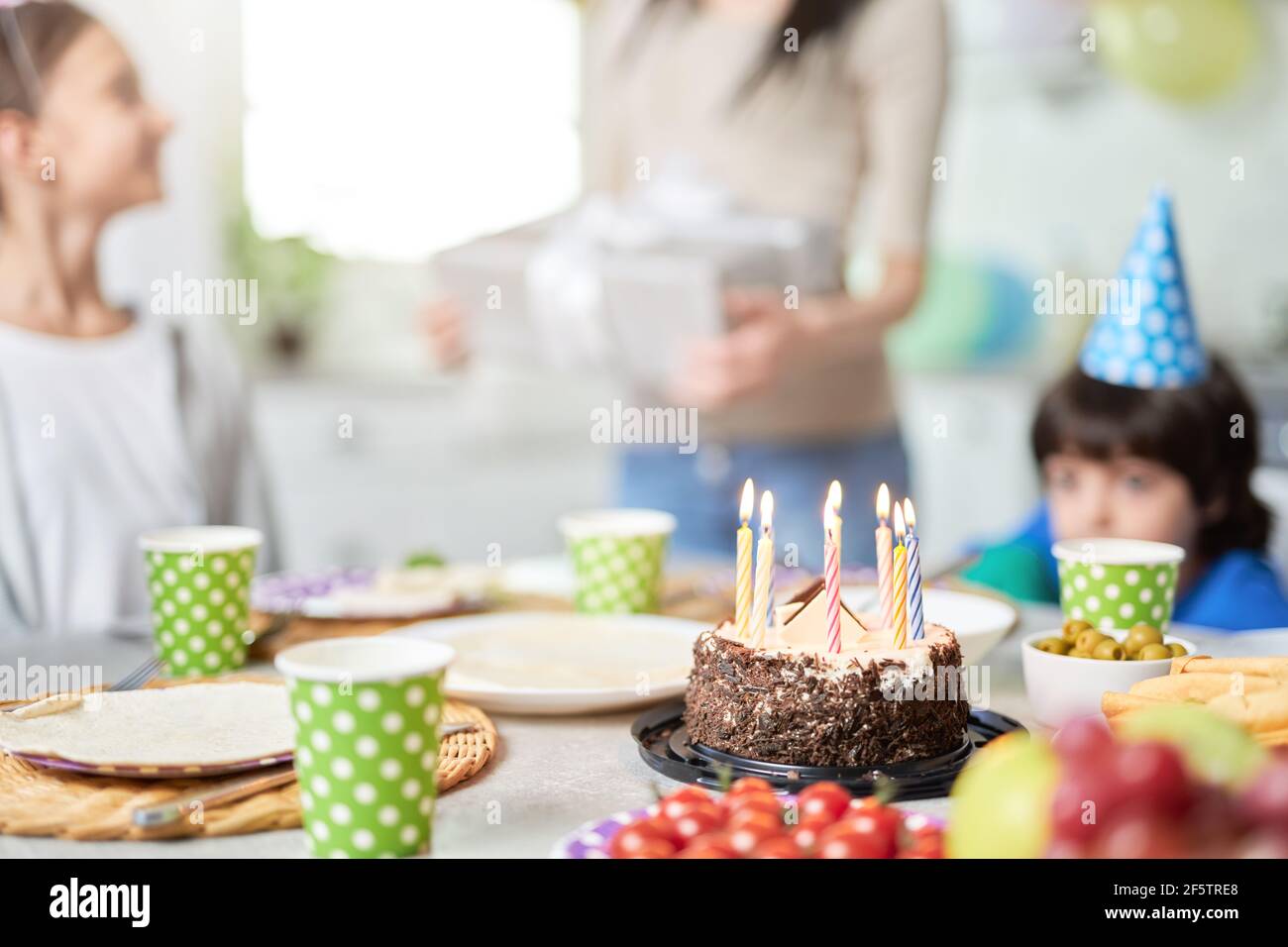 Close up of a birtday cake with candles on the table. Happy latin american family with children celebrating birthday at home Stock Photo