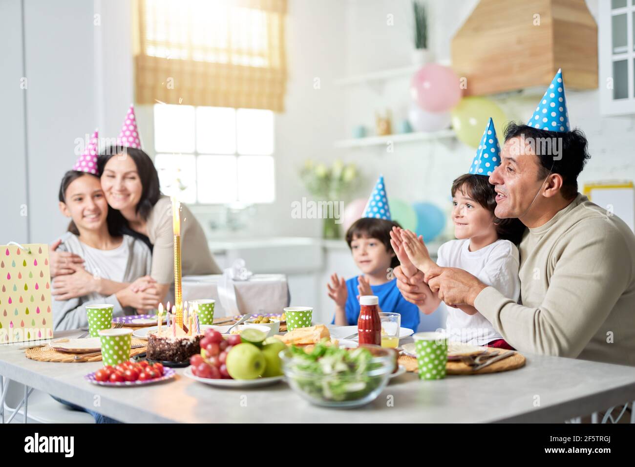 Joyful day. Happy latin american family with children looking suprised about firework sparkler on a cake while celebrating birthday together at home Stock Photo