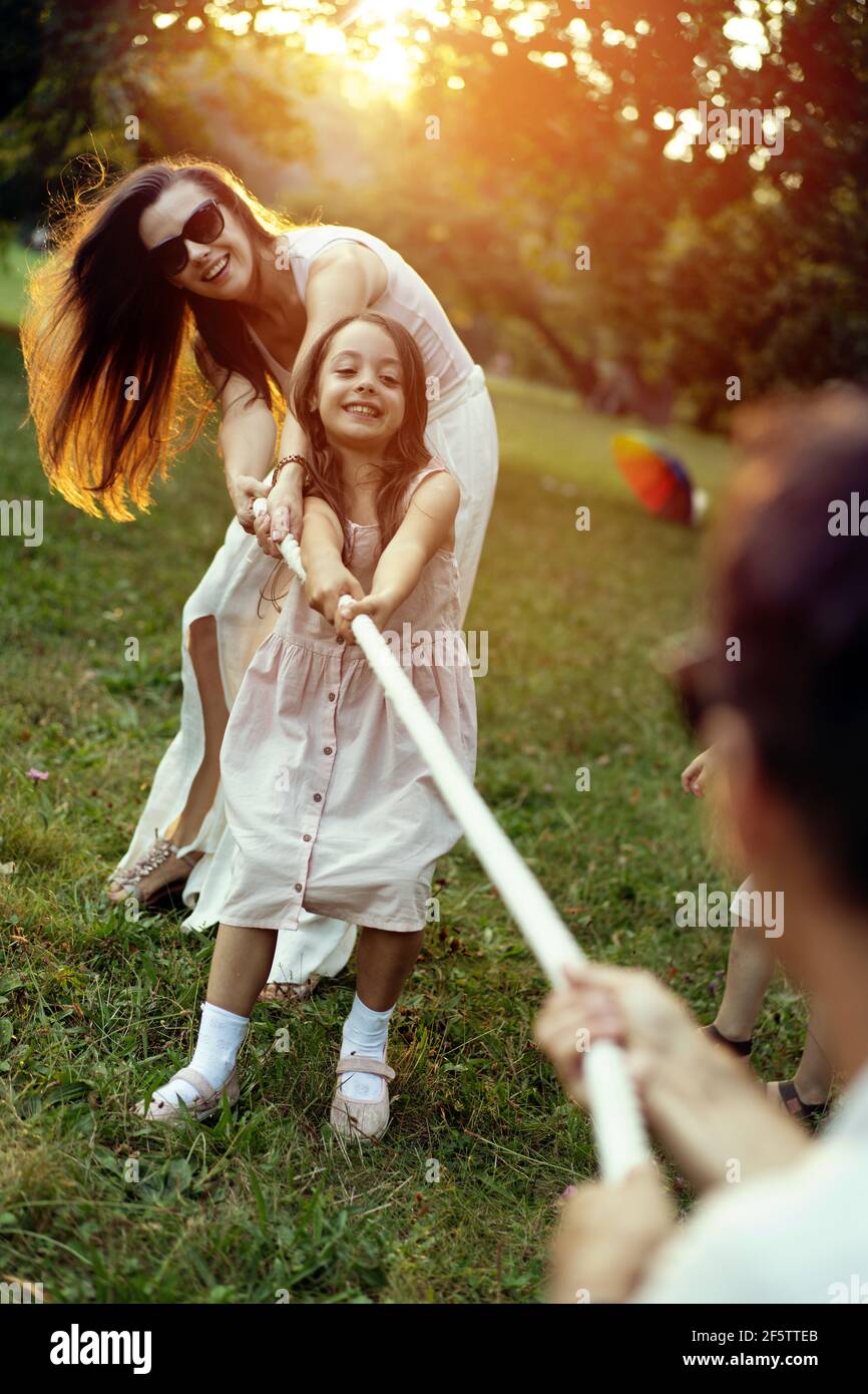 Joyful, young family playing tug-of-war in the park Stock Photo