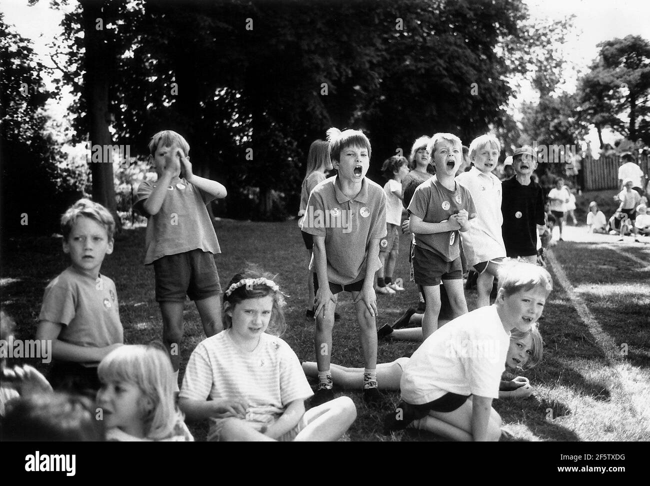 Children cheer on classmates taking part in a race at an Infants School Children Sports Day at RAB Infants School in Saffron Walden Essex Dbase Stock Photo