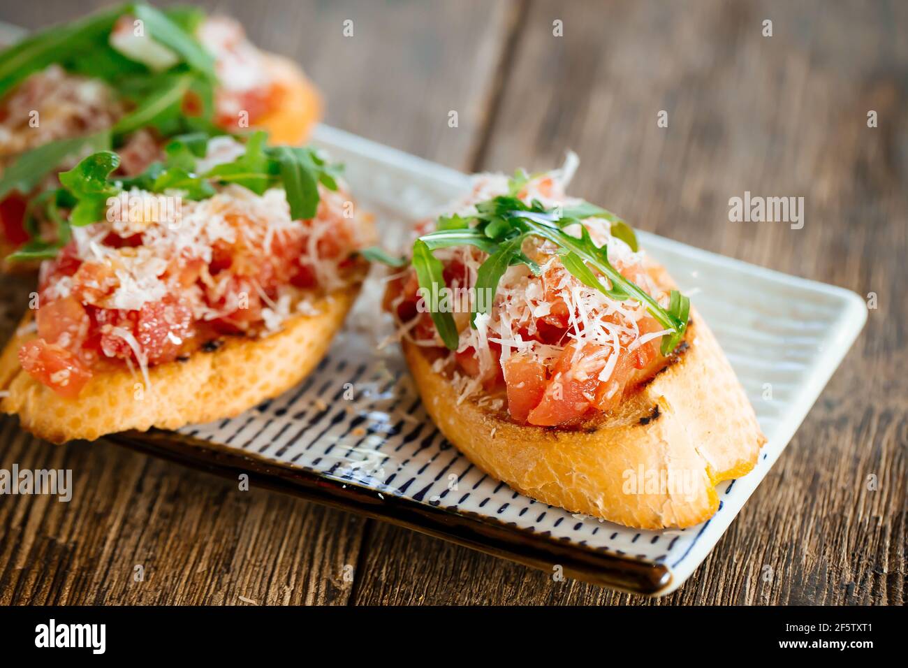 Salmon bruschettas with grated cheese and arugula Stock Photo