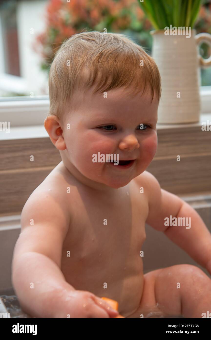 A baby being bathed in a kitchen sink Stock Photo