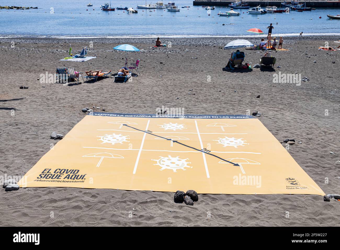 Large banner with graphic design to demonstrate the two metre social distancing rules to be maintained due to Covid 19 on the beach at Playa San Juan, Stock Photo