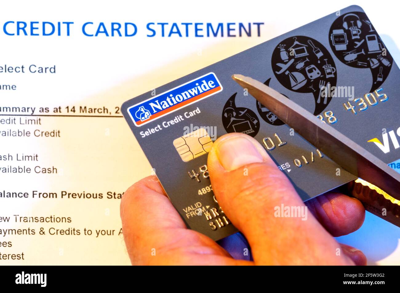 Credit card statement with hand cutting up card, either to avoid debt or prevent identity theft. Stock Photo