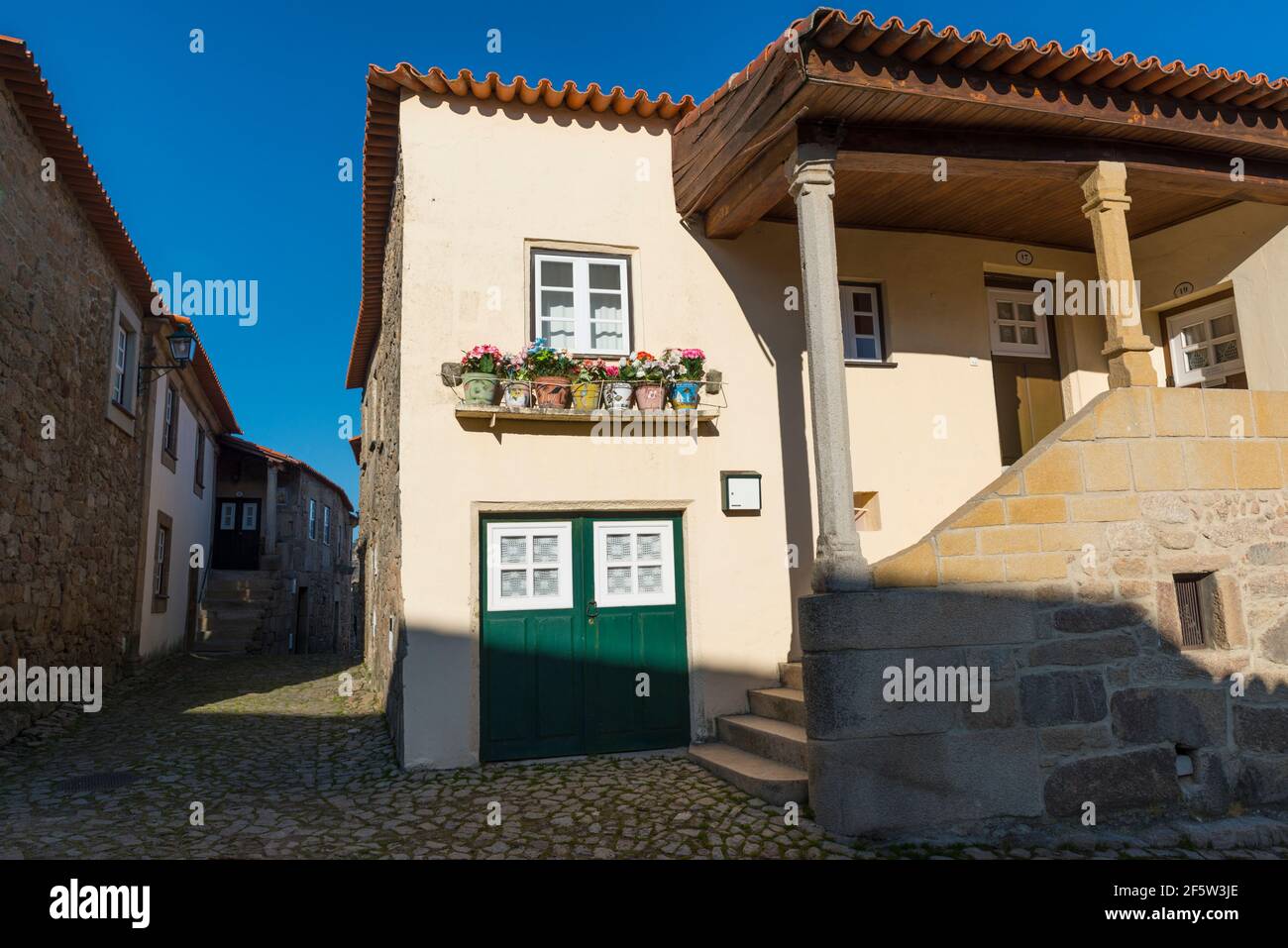 The village Castelo Mendo, Almeida district, Portugal. Flowerpots with colorful artificial flowers under a window Stock Photo