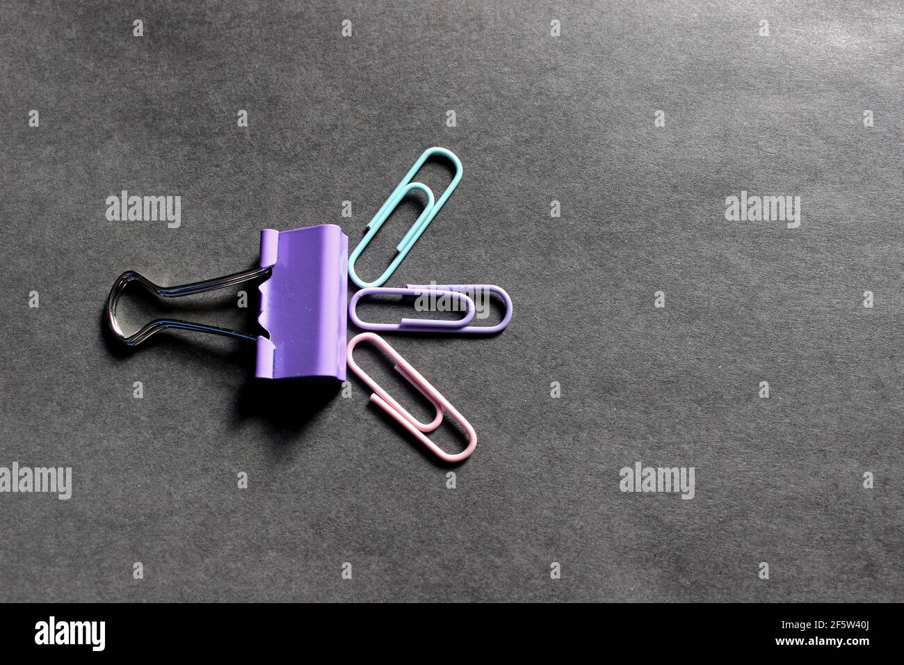 Multicolored paper clips on a dark background Stock Photo