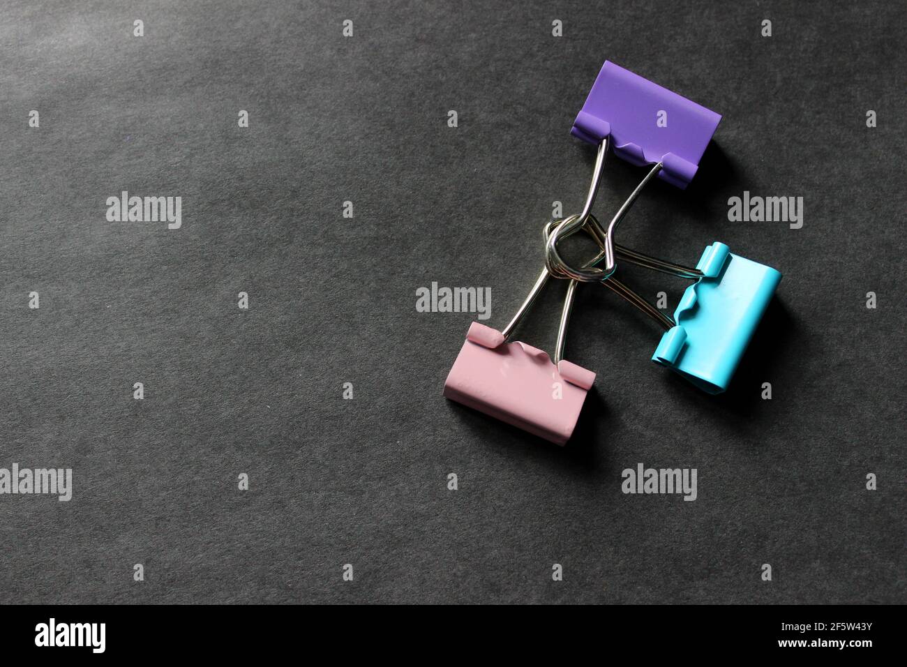 Multicolored paper clips on a dark background Stock Photo