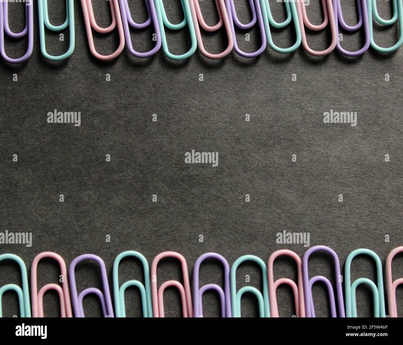 Multicolored paper clips on a dark background Stock Photo