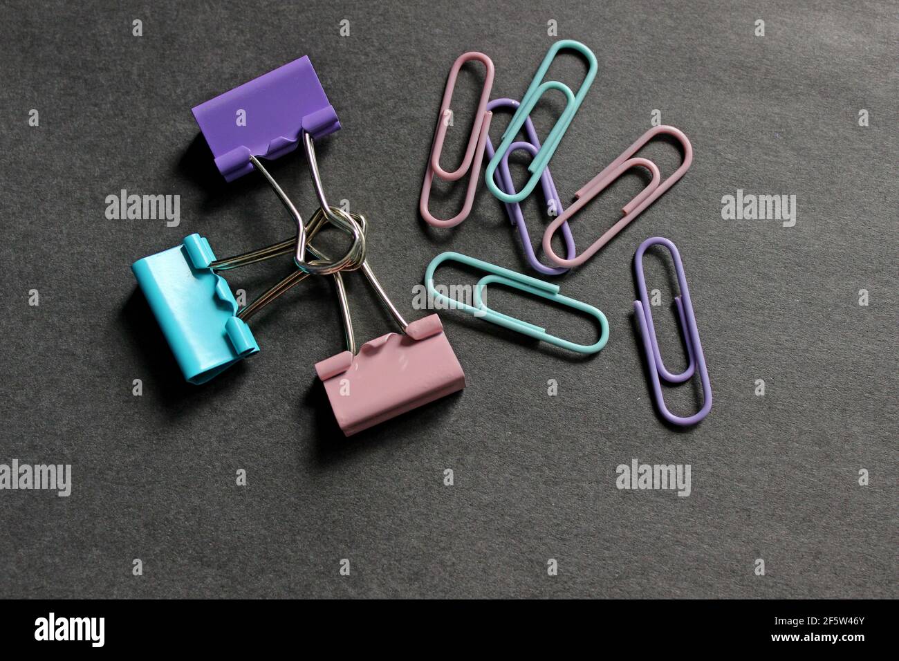 Multicolored paper clips on a dark background Stock Photo