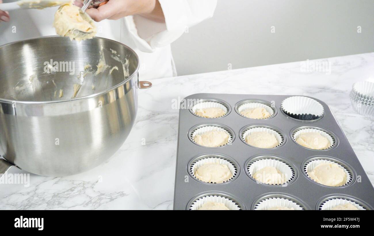 Step by step. Scooping batter with batter scooper into cupcake pan lined  with paper cupcake liners Stock Photo - Alamy