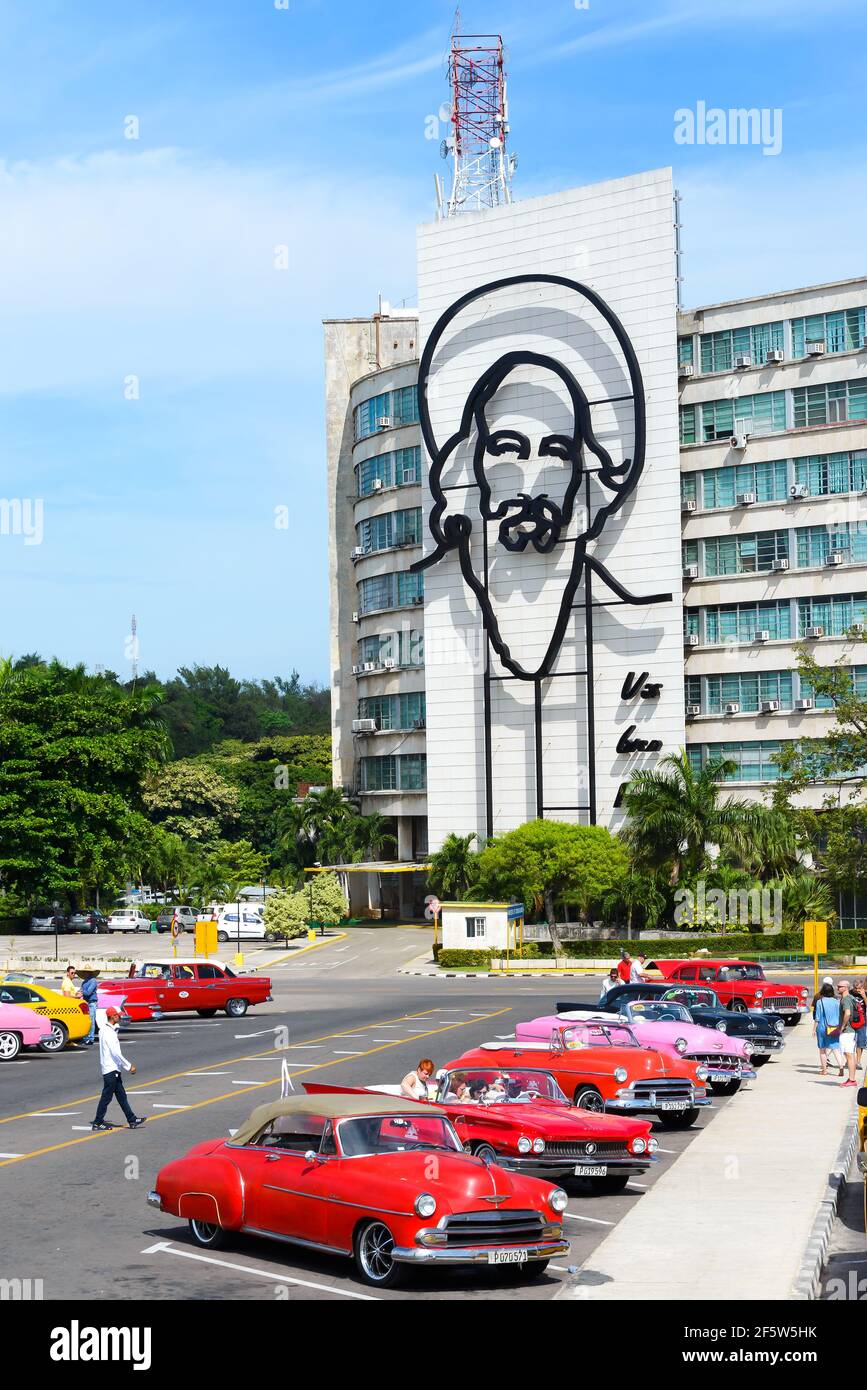 Ministry of Information and Communications building with Camilo Cienfuegos mural and old classic cars in Revolution Square, Havana, Cuba. Stock Photo