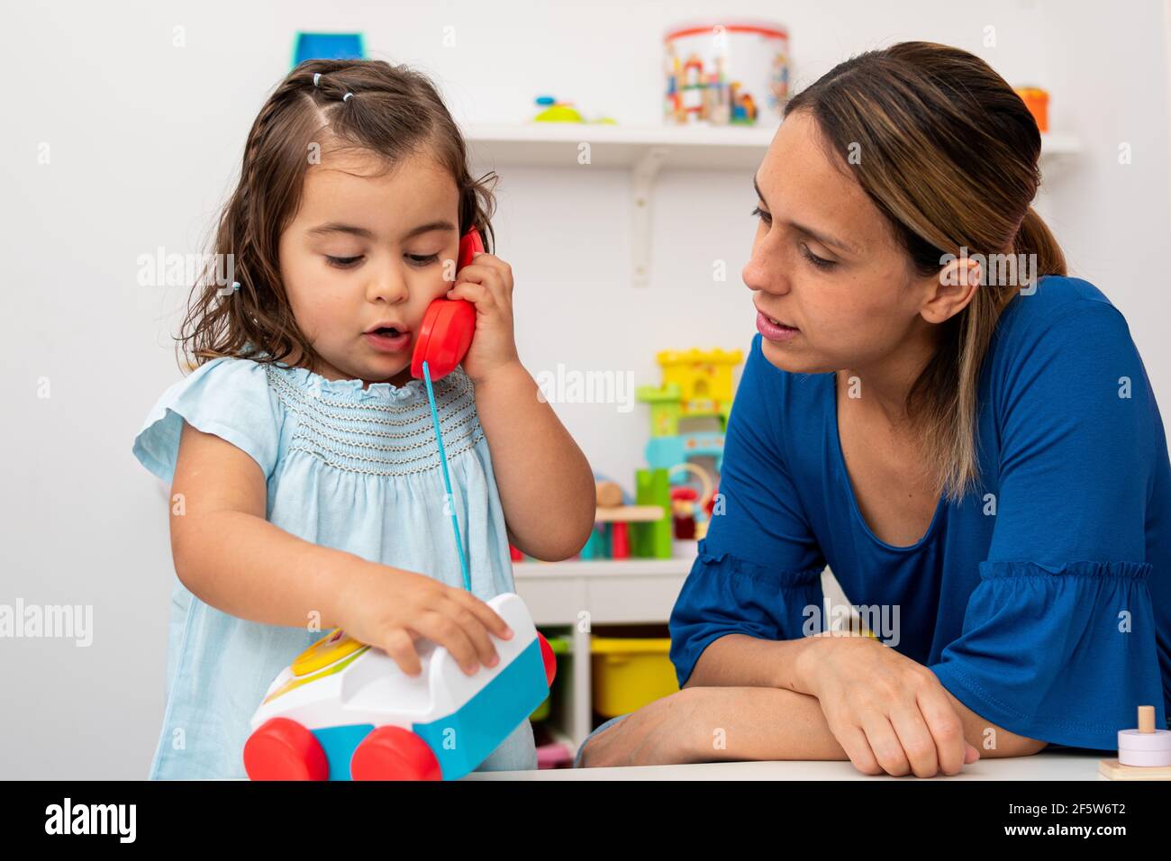 Twoyearold girl and her young kindergarten teacher, both Caucasian