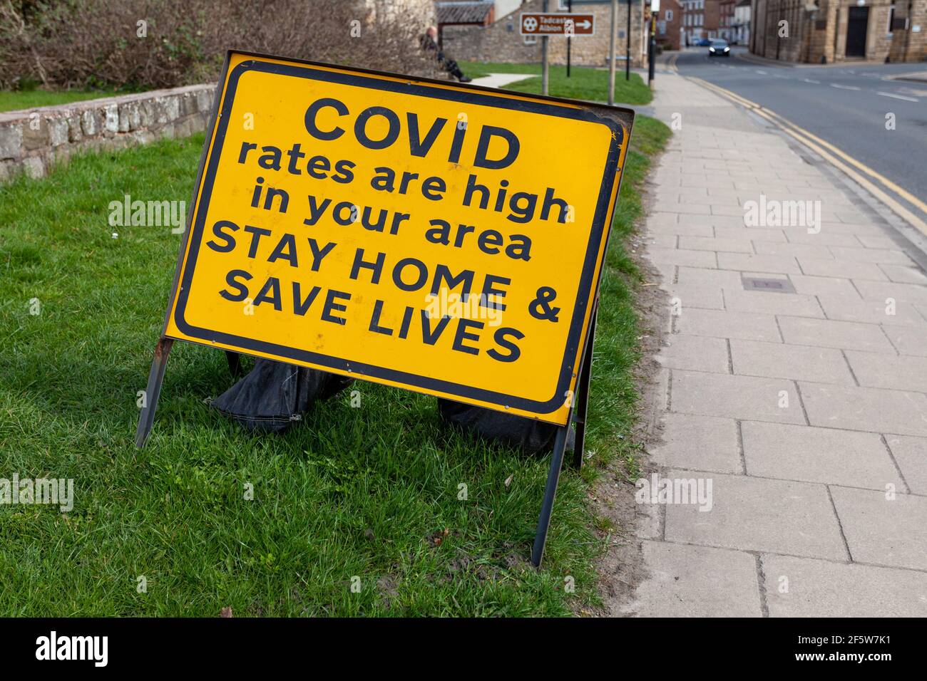 Covid 19 yellow and black roadside warning sign - High rates, stay home, save lives Stock Photo