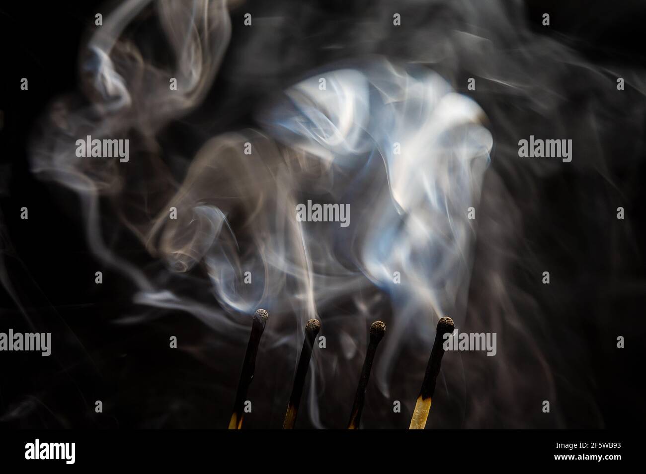 several burnt matches with white smoke on a black background Stock Photo