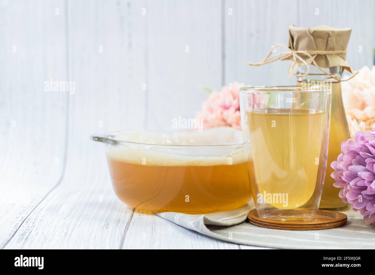 Kombucha tea in glass on wood background, cider fermented drink
