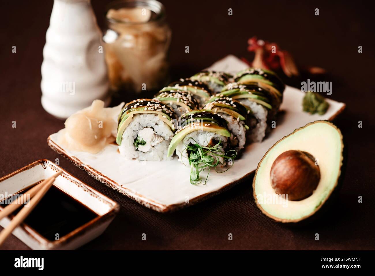 Close-up of a set of sushi rolls with an avocado cut in half lying next to it Stock Photo