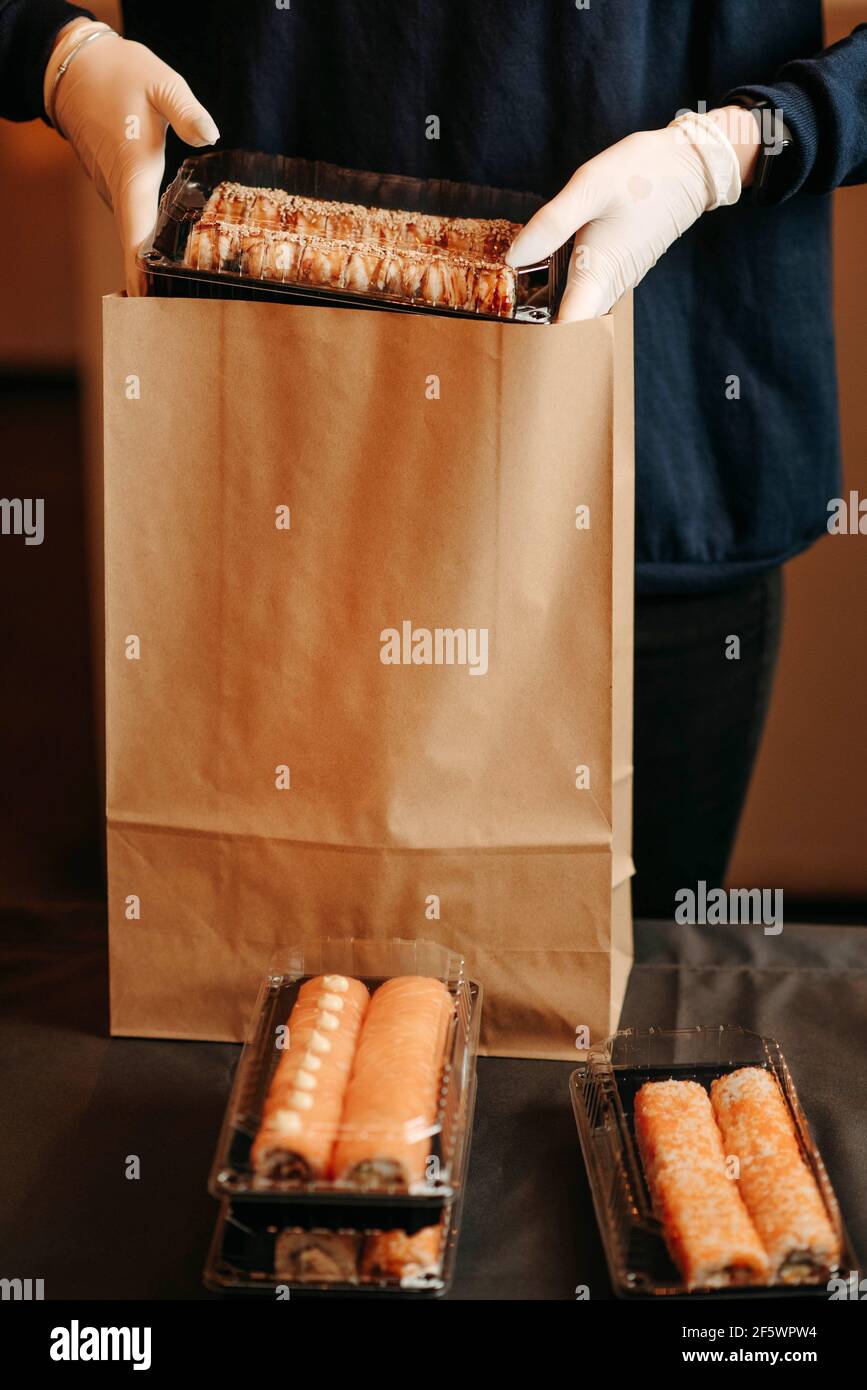 Woman in white gloves packing takeaway sushi Stock Photo