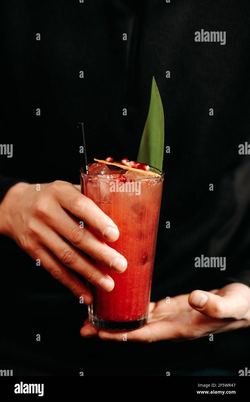 A client stands near a bar counter in a cafe with a cocktail in his hands Stock Photo