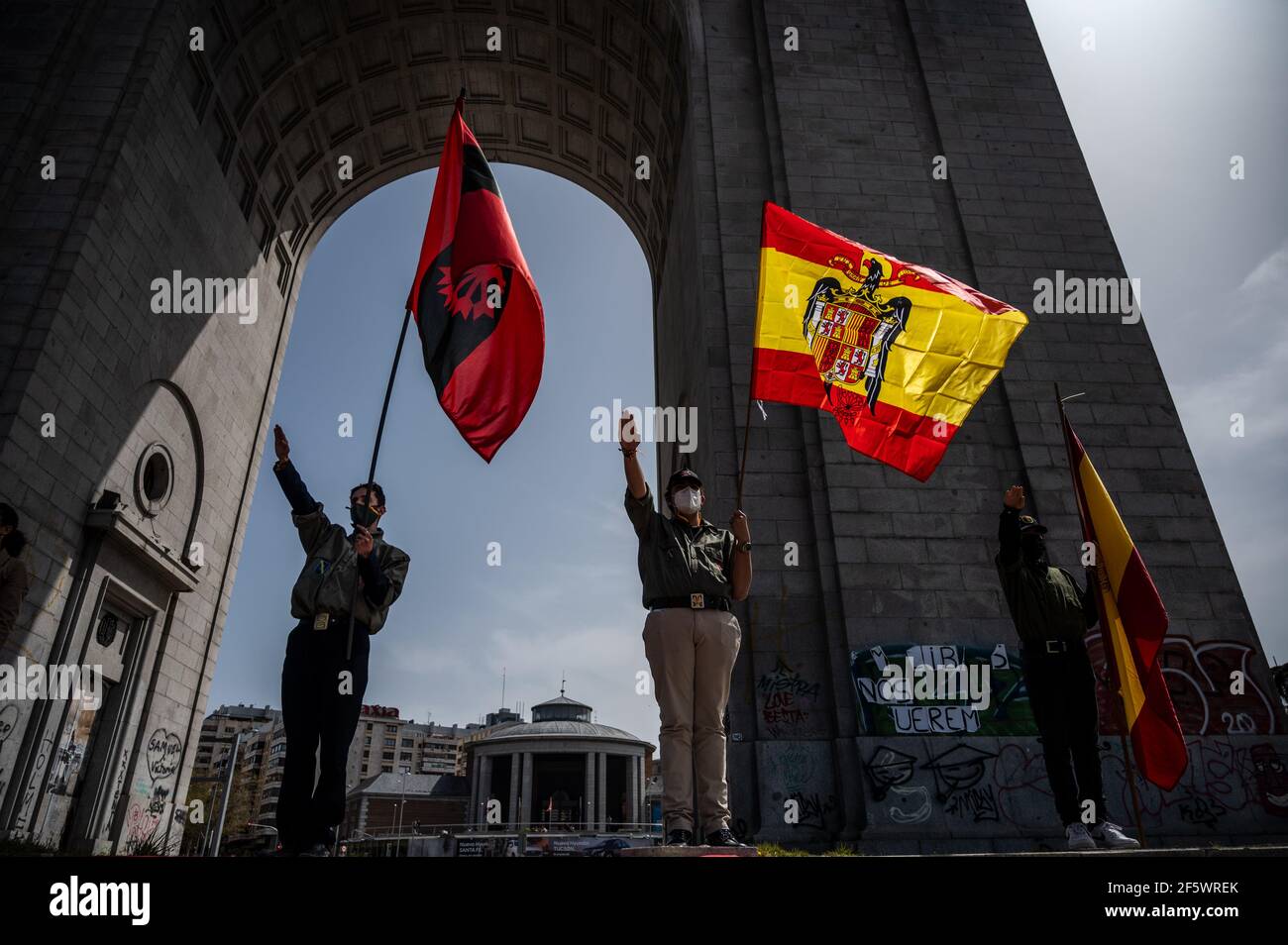 Madrid, Spain. 28th Mar, 2021. Supporters of Franco dictator doing the fascist salute holding pre-constitutional Spanish flags during a gathering of far right wing supporters at Arco de la Victoria, commemorating the 82nd anniversary when dictator Francisco Franco and his forces entered Madrid following the Spanish Coup of July 1936 against the 2nd Spanish Republic. Credit: Marcos del Mazo/Alamy Live News Stock Photo