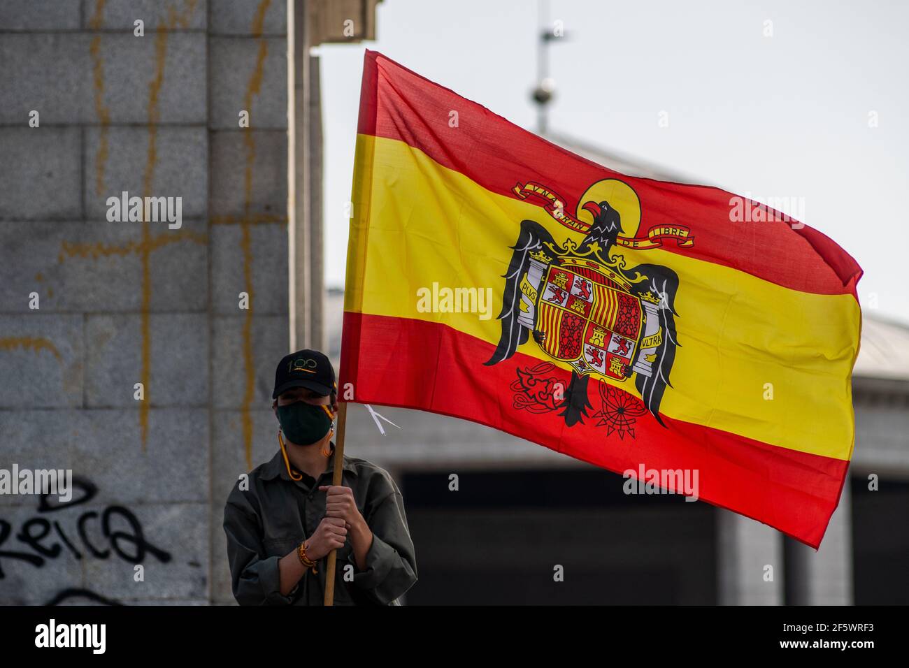 Madrid, Spain. 28th Mar, 2021. A supporter of Franco dictator holding a pre-constitutional Spanish flag during a gathering of far right wing supporters at Arco de la Victoria, commemorating the 82nd anniversary when dictator Francisco Franco and his forces entered Madrid following the Spanish Coup of July 1936 against the 2nd Spanish Republic. Credit: Marcos del Mazo/Alamy Live News Stock Photo