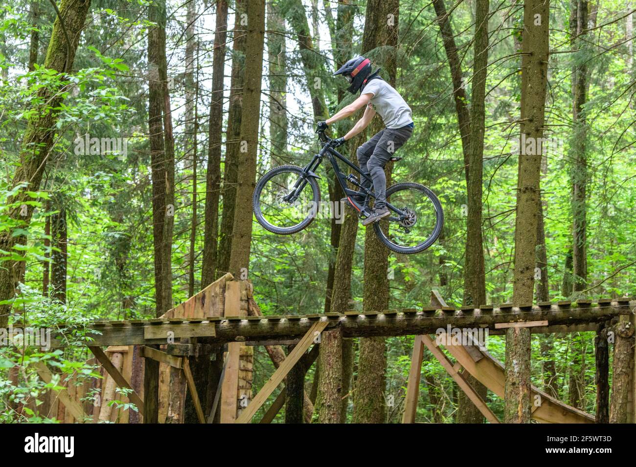 Jump session of professional young mountainbikers in a bike park in forest Stock Photo