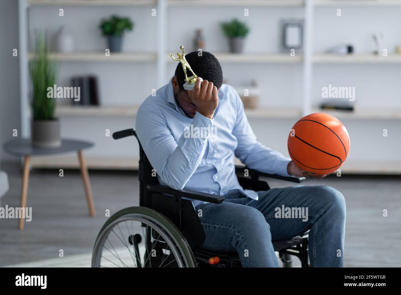 Young black basketball player in wheelchair holding ball and feeling