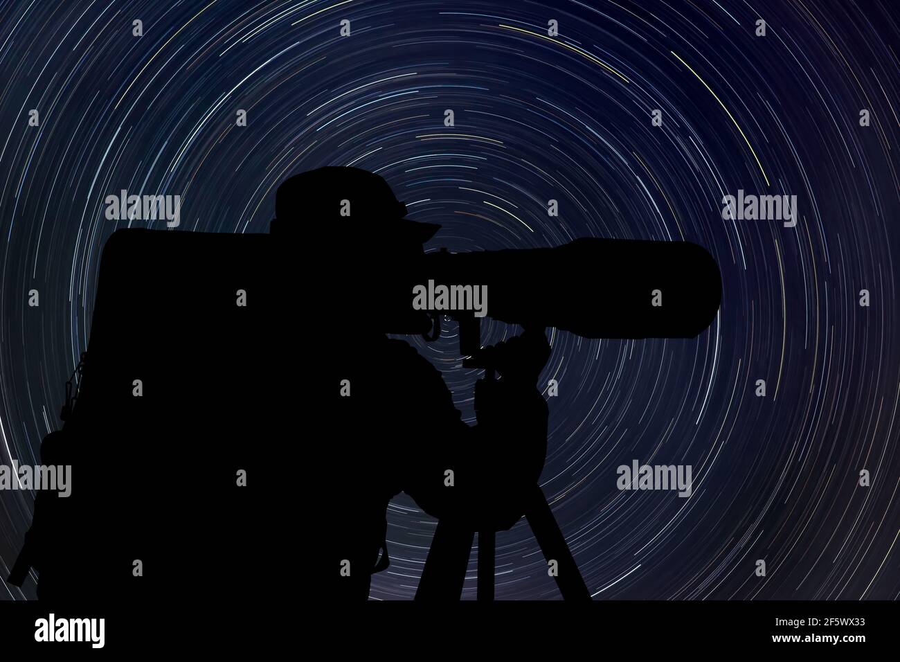 Silhouette of wildlife photographer at night with startrail in the background Stock Photo