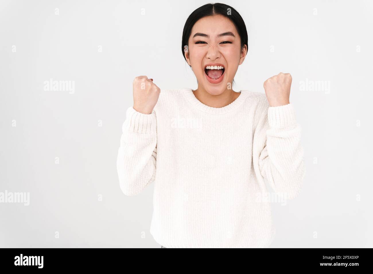 Asian excited nice girl screaming and making winner gesture isolated ...