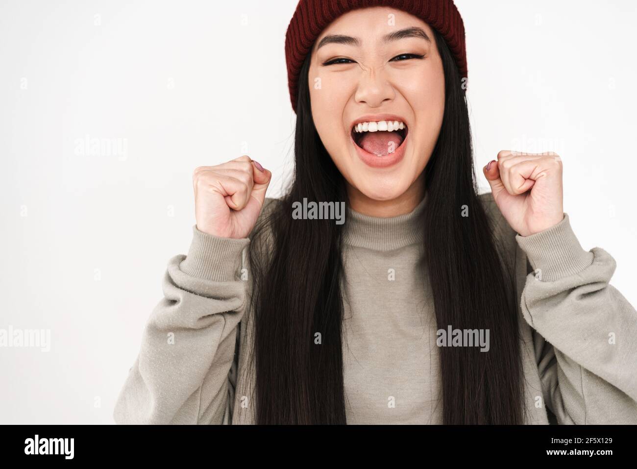 Asian excited nice girl screaming and making winner gesture isolated ...