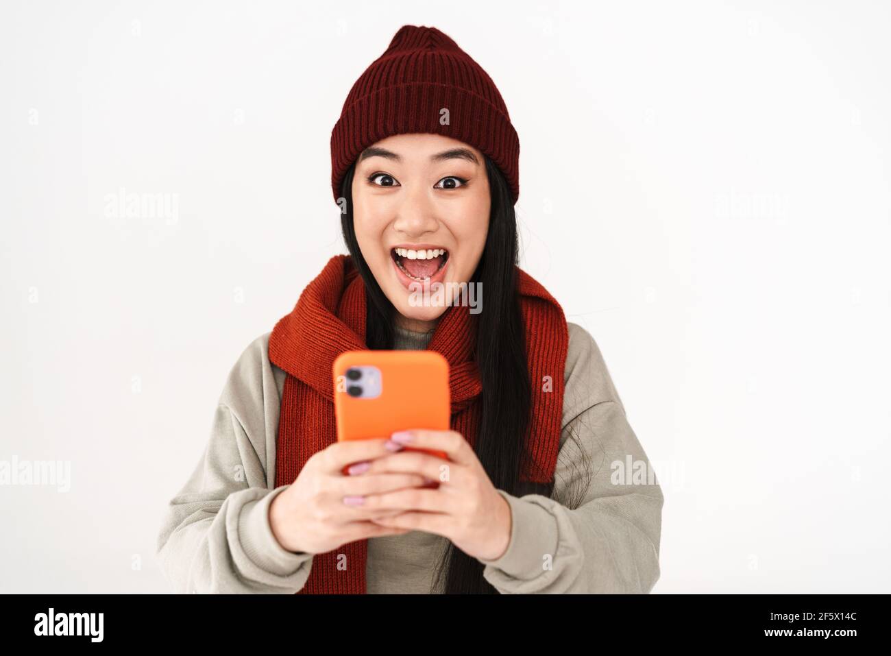 Asian excited nice girl exclaiming while using mobile phone isolated ...