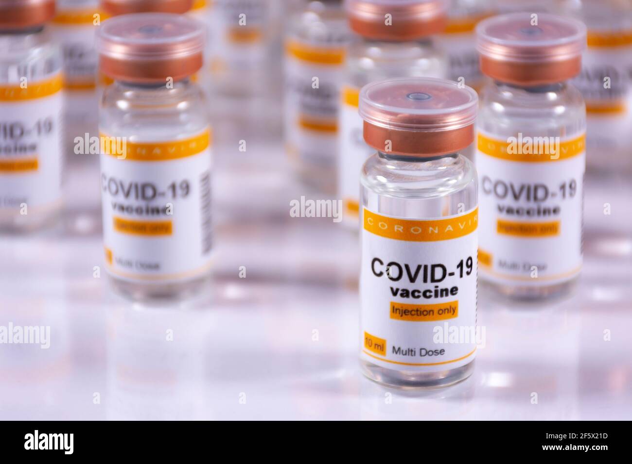 Coronavirus vaccine vials on a white table with reflections. Laboratory ...