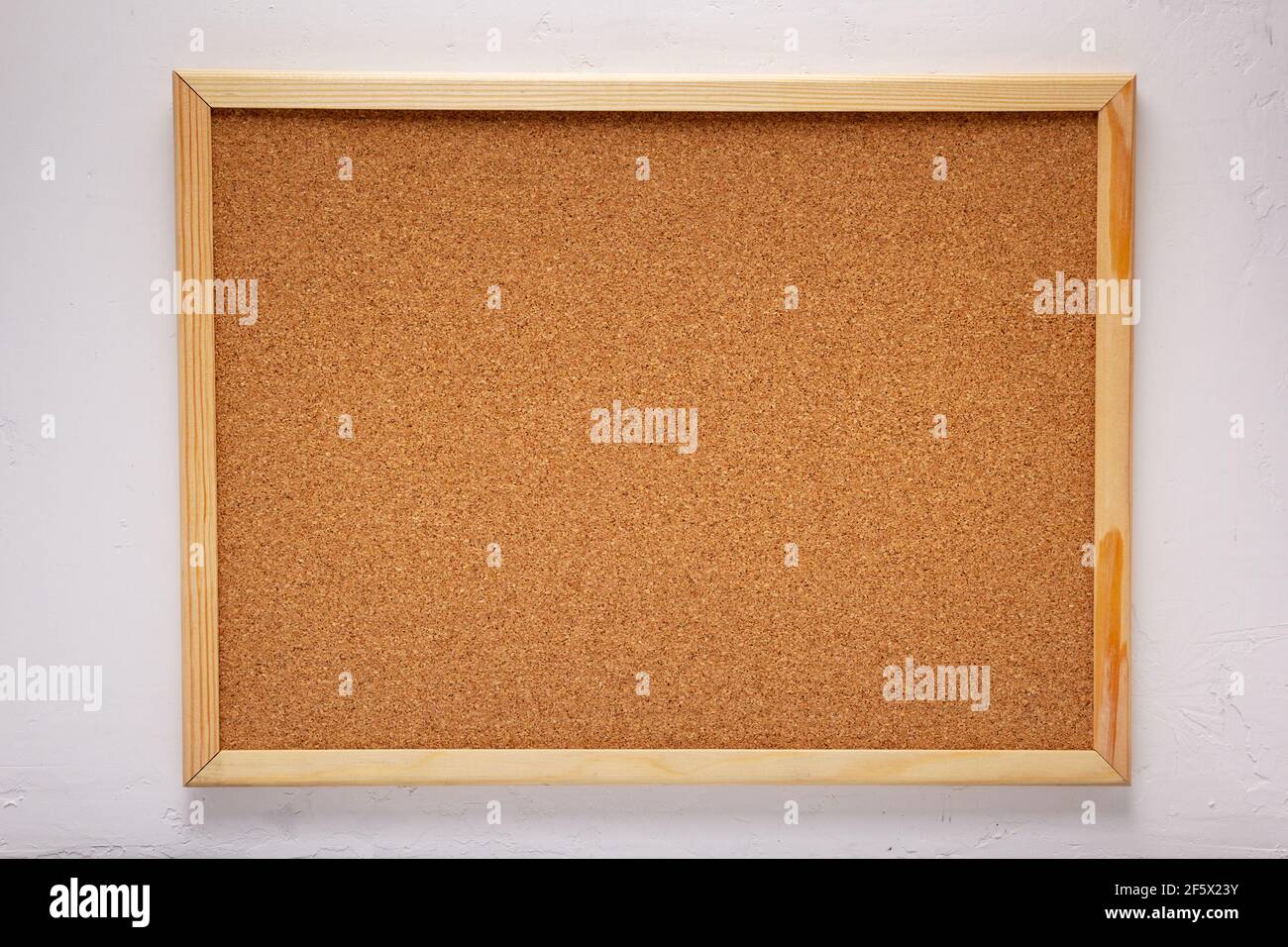 cork board or corkboard at white concrete or putty wall background