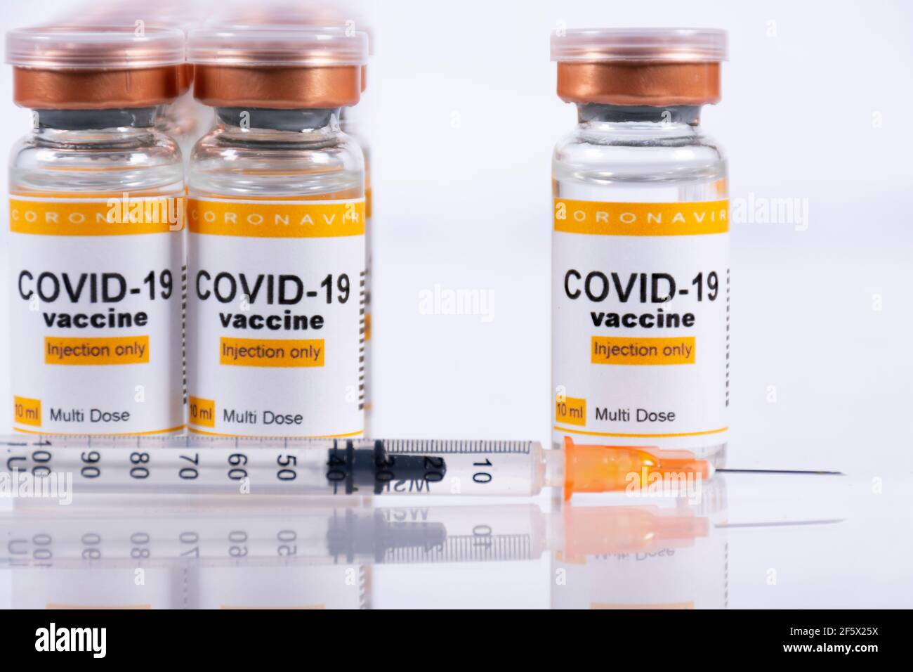 Vials with coronavirus vaccine on white table with reflections. Laboratory or healthcare facility concept Stock Photo