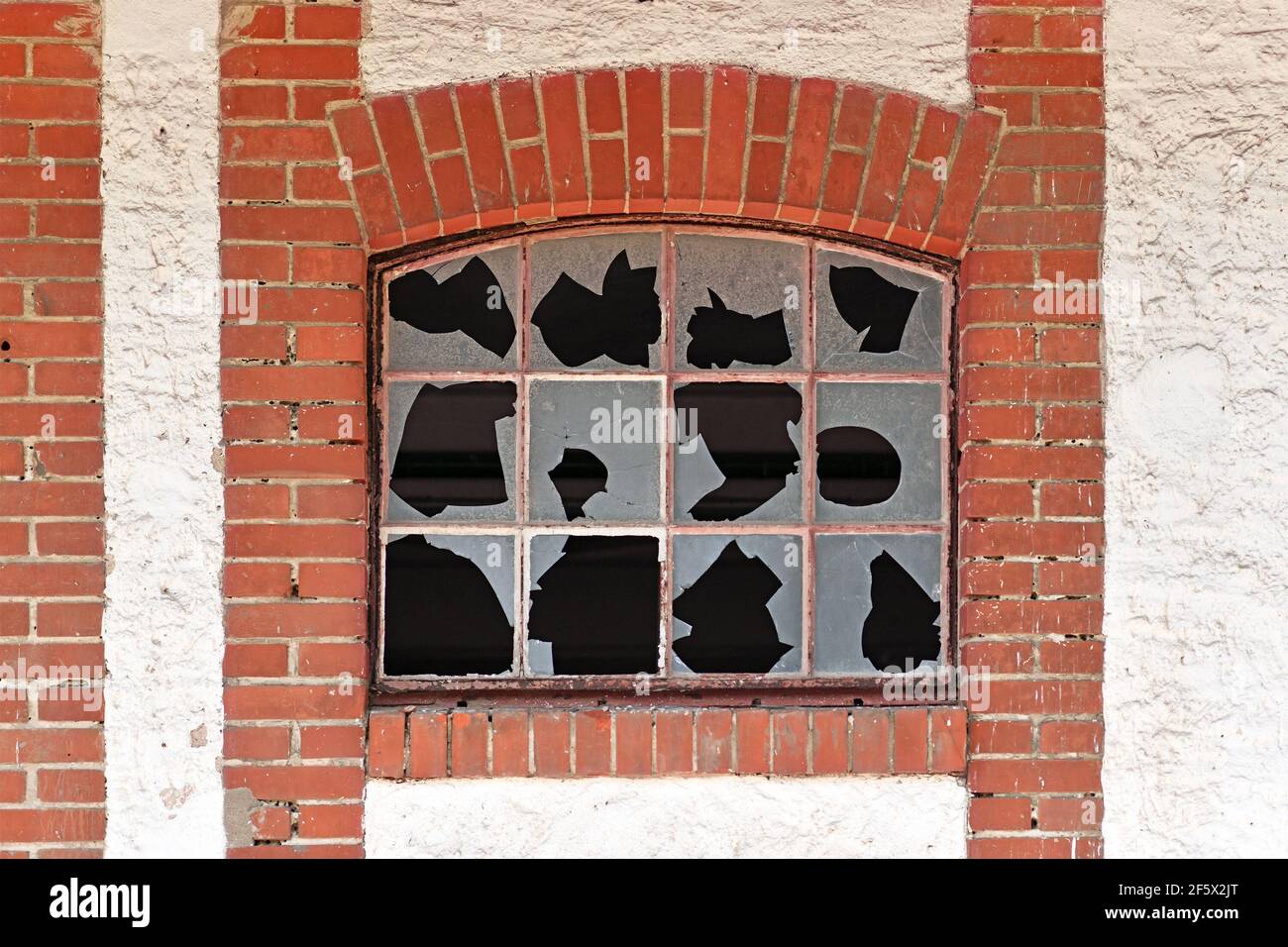Old muntin window with broken glass of old abandoned building with red brick wall frame Stock Photo