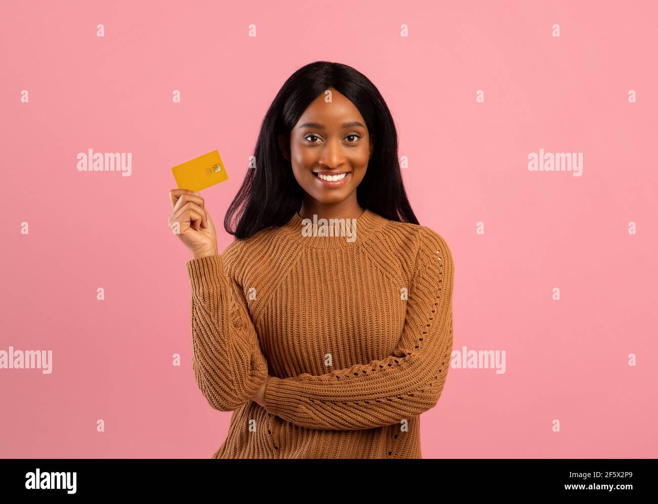 Young black woman with credit card looking at camera and smiling over pink studio background Stock Photo