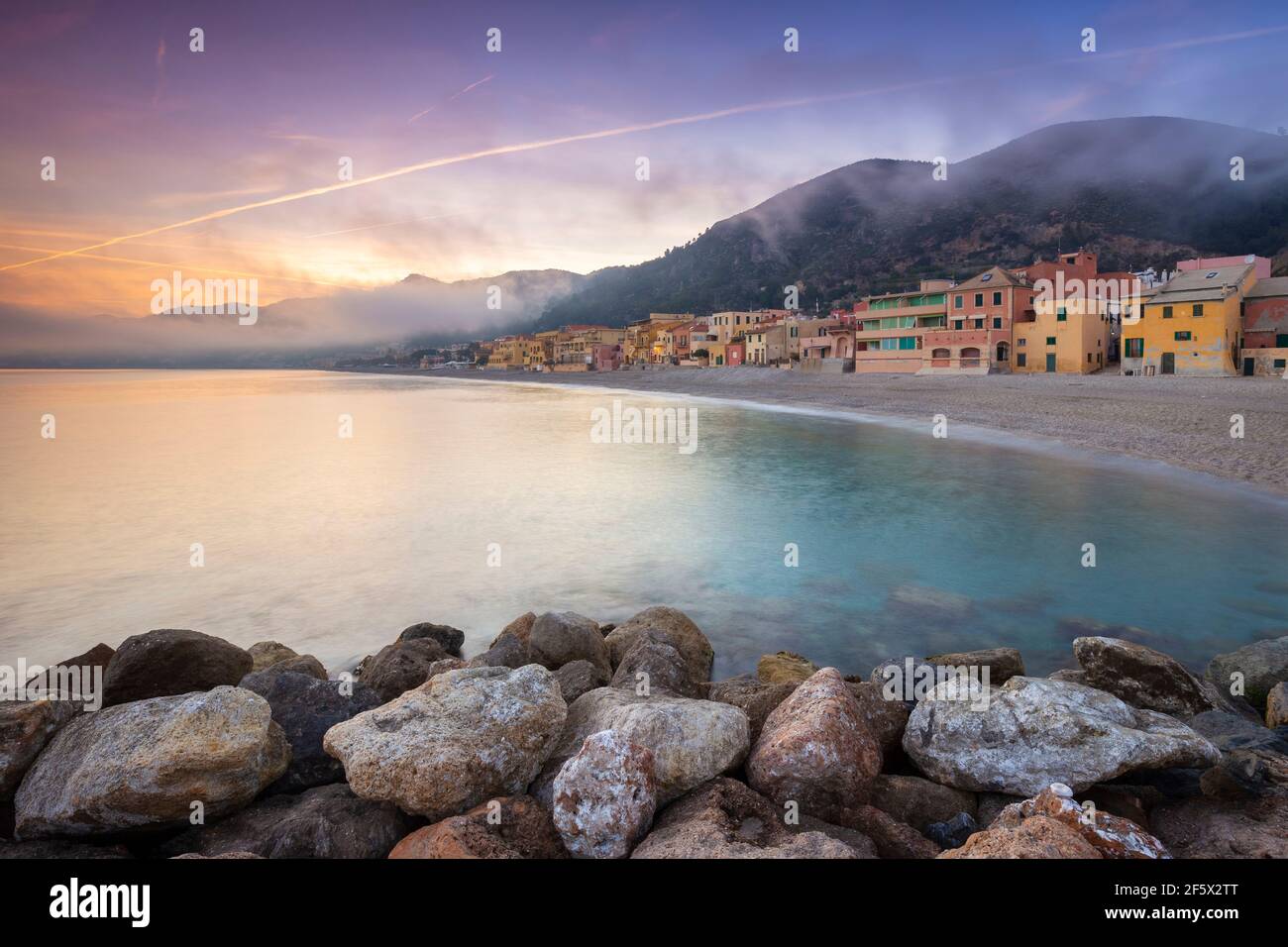 Foggy sunset over the colorful houses and the beach of Varigotti, Finale Ligure, Savona district, Ponente Riviera, Liguria, Italy. Stock Photo