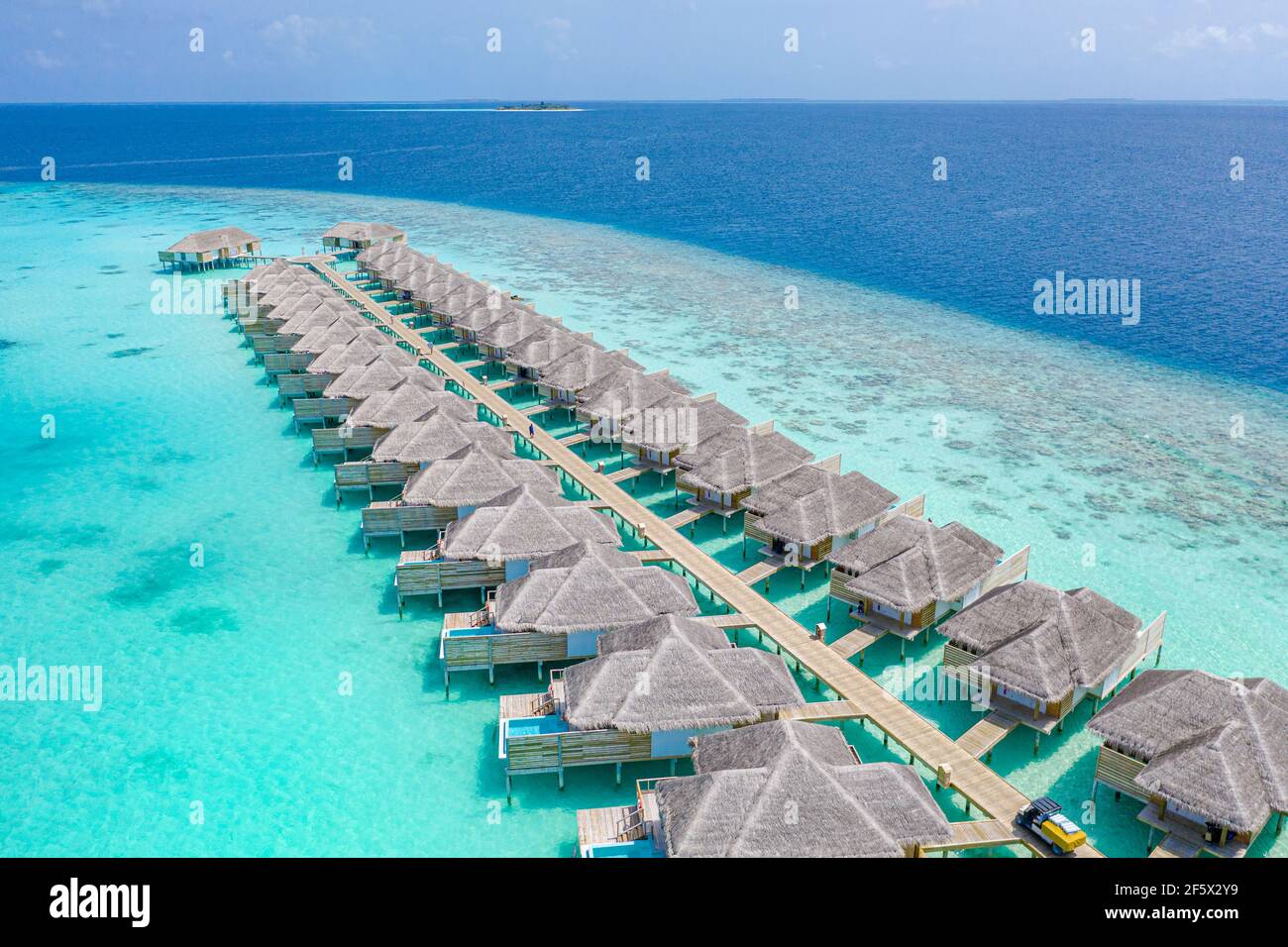 Aerial view of Maldives island, luxury water villas resort and wooden pier. Beautiful sky and ocean lagoon beach background. Summer vacation holiday Stock Photo