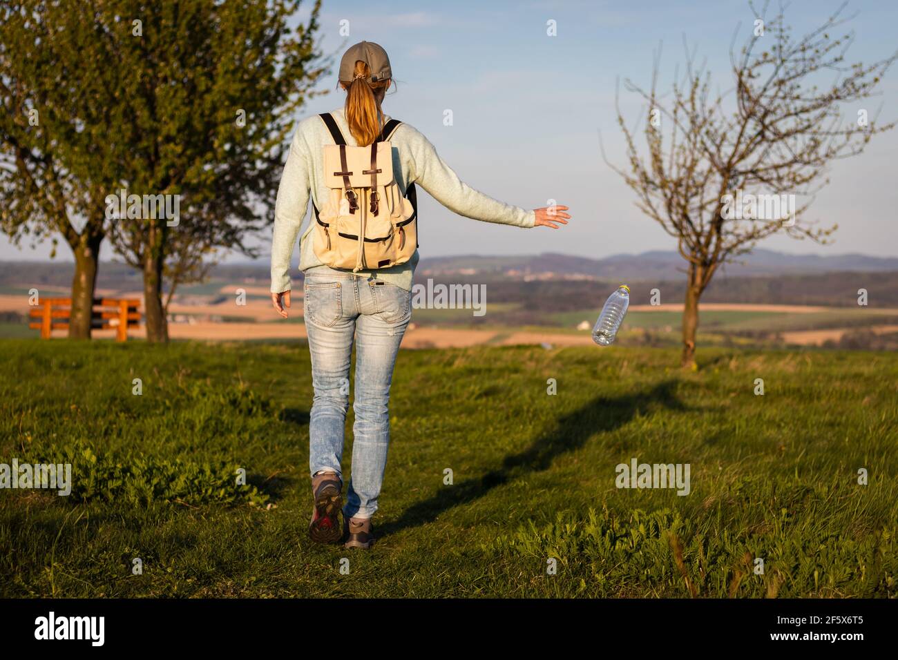 Irresponsible tourist throwing away water bottle in nature. Environmental issues. Environmental damage by plastic waste. Stock Photo