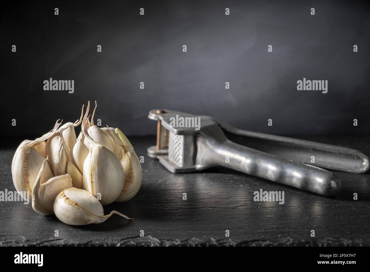 Garlic bulb and a garlic press. Stock Photo