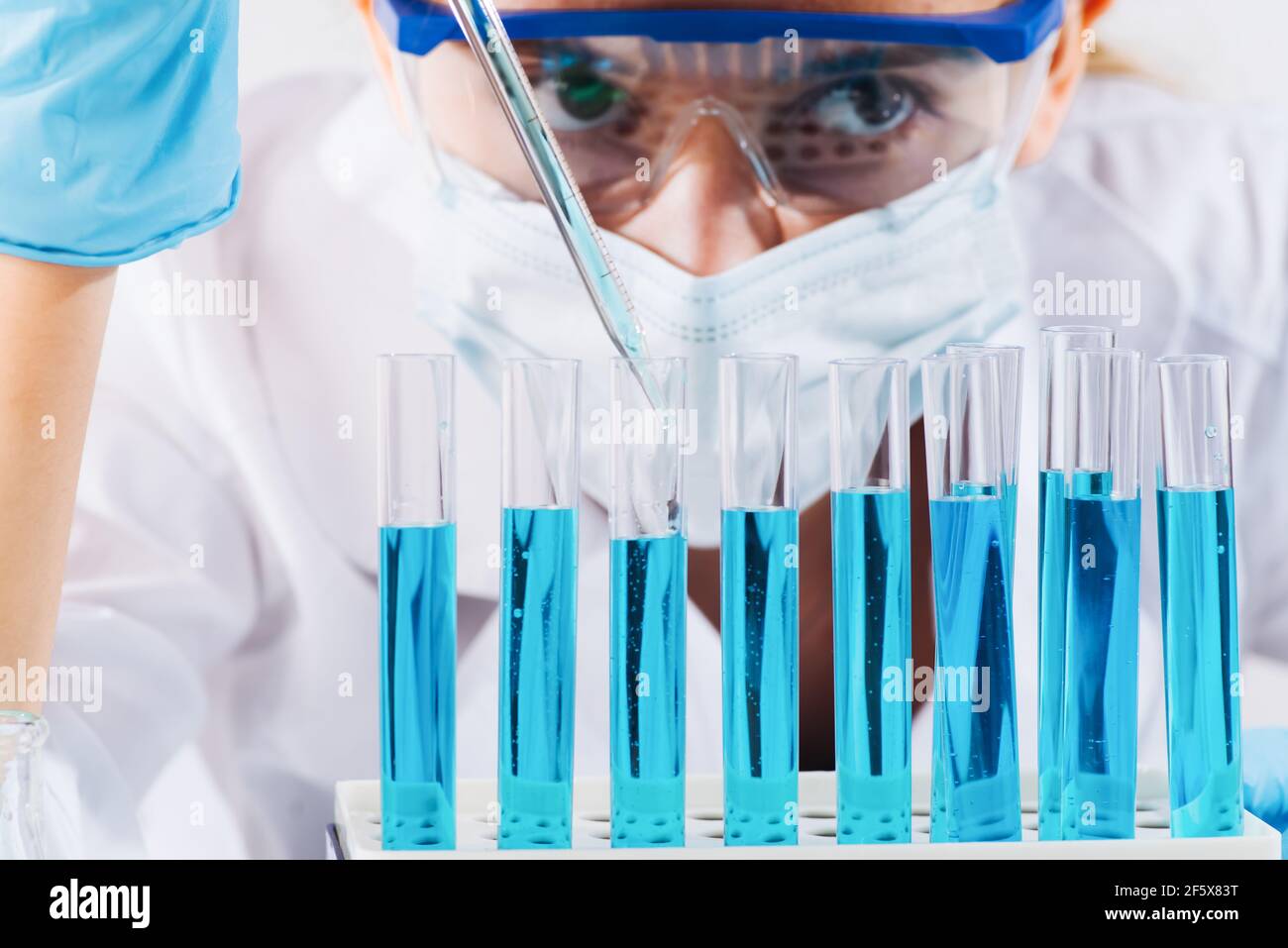 Female Research Scientist Uses Micropipette Filling Test Tubes.A