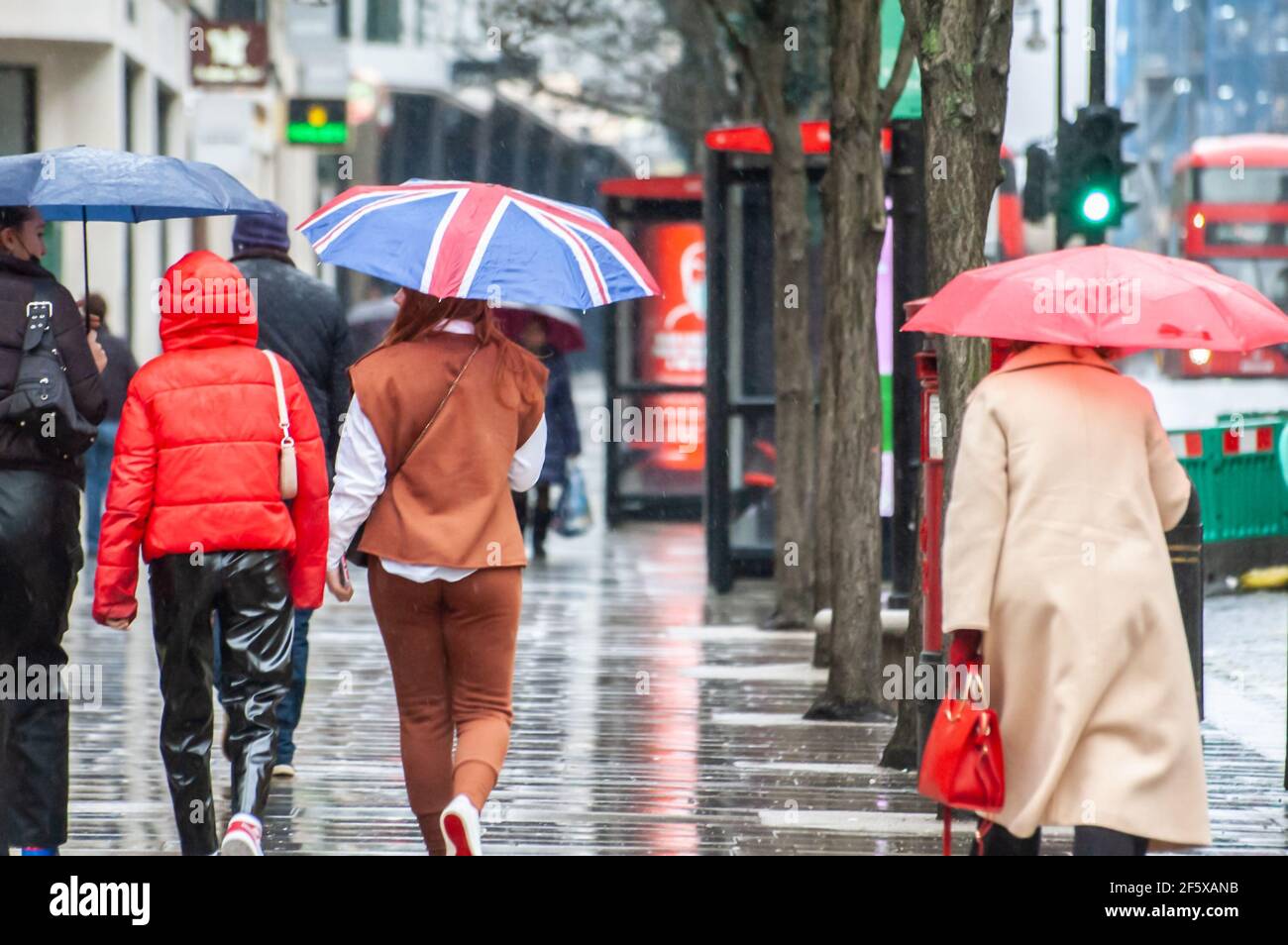 OXFORD STREET, LONDON, ENGLAND- 17th February 2021: Woman with a Union flag umbrella, on a rainy day on Oxford Street Stock Photo