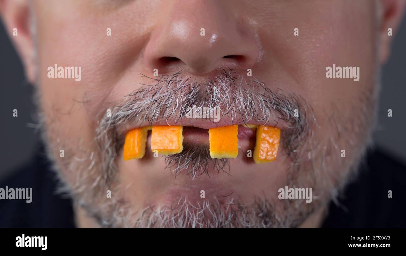 Man playing with orange peel. Fake teeth Stock Photo