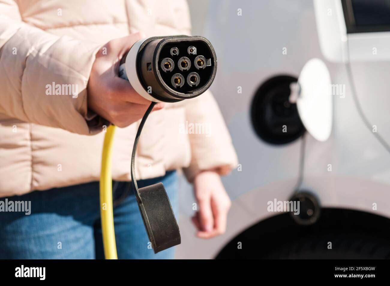 Car power charger in woman hand. Power supply for recharging of electric or EV car Stock Photo