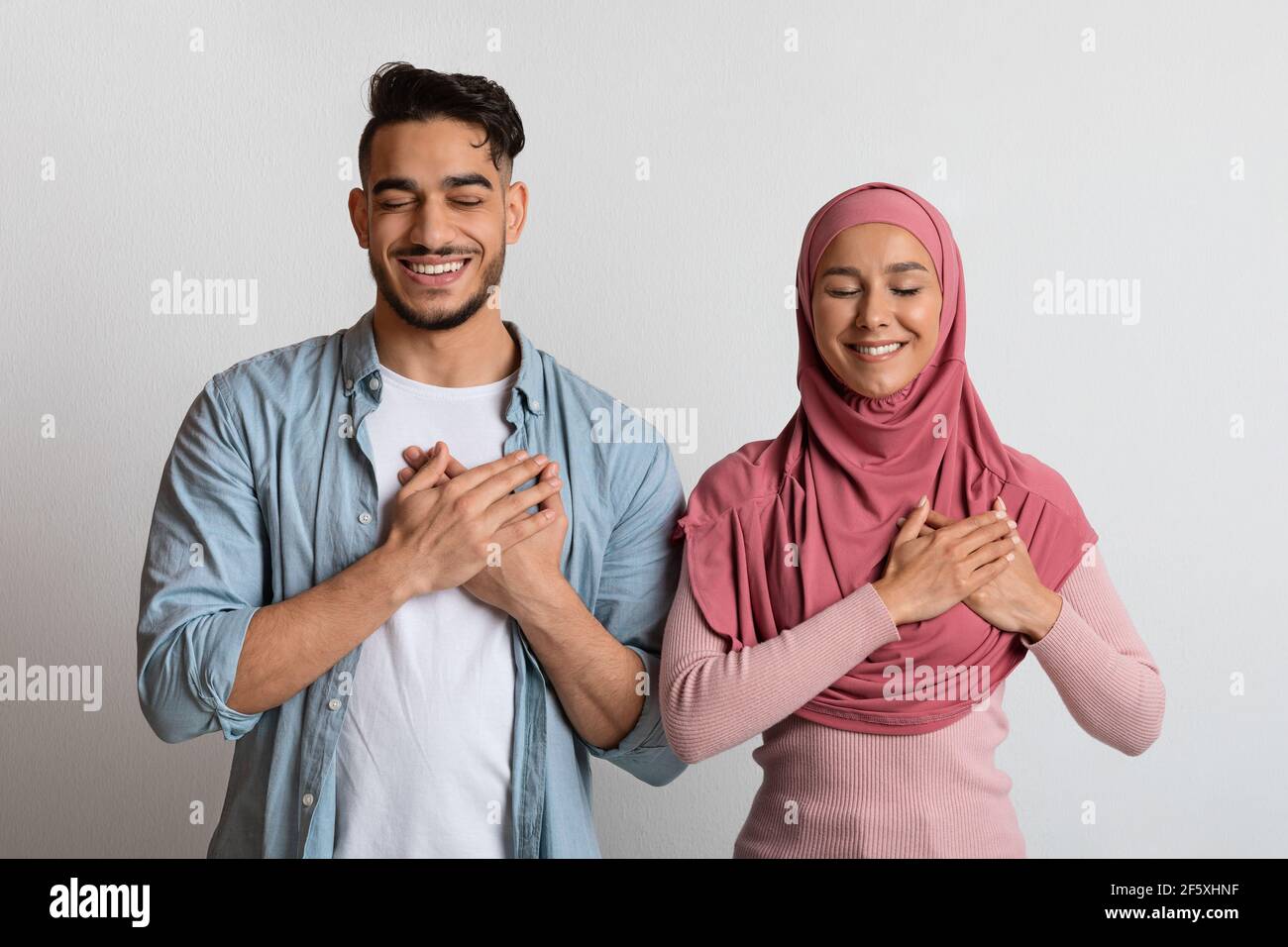Thankful Muslim Couple Keeping Hands On Chest Expressing Gratitude Together Stock Photo