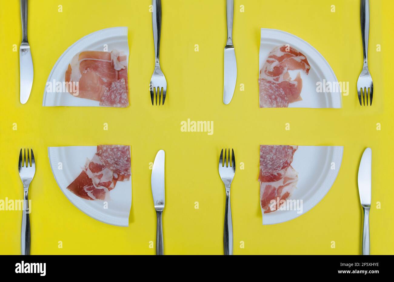 Cut portions of Antipasto misto. On a yellow surface, four table services made of four quarters of deli meat plates.. Stock Photo