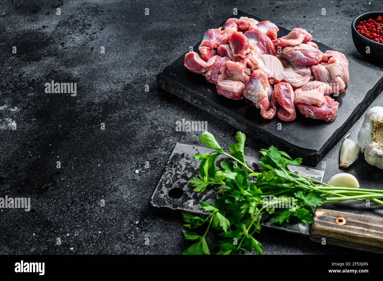 Raw uncooked Bird chicken giblets gizzards, stomachs. Black background